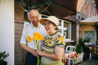 Happy elderly couple holding yellow flowers